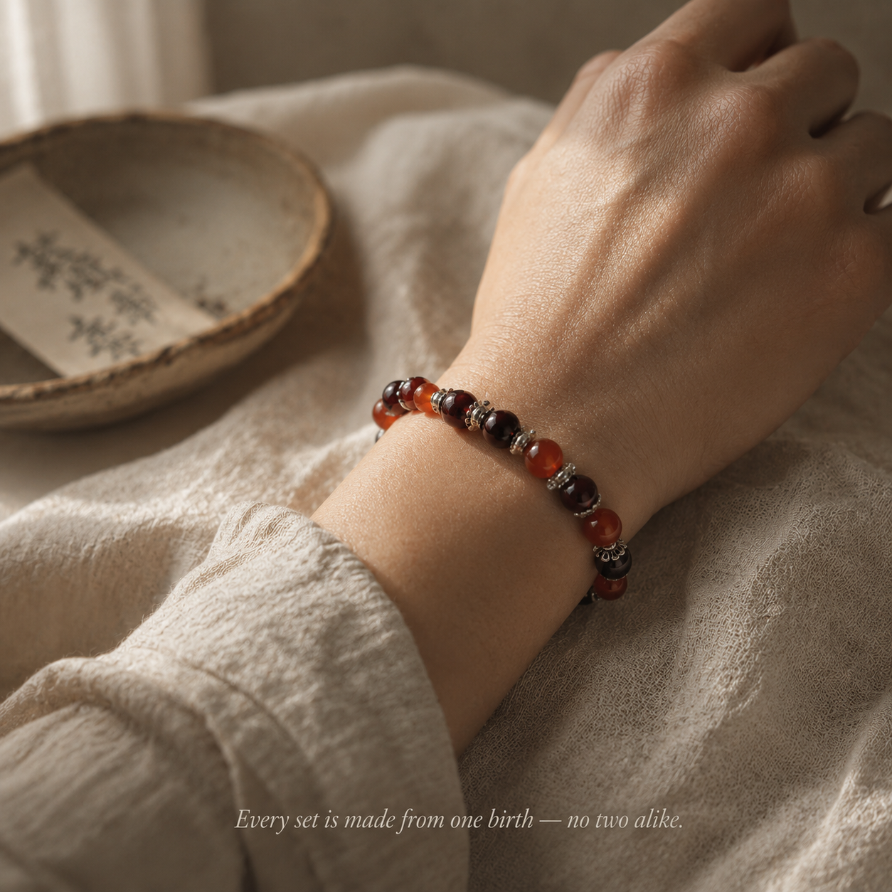 An alignment bracelet set made from personally selected crystals and birthstones, draped on a warm linen surface — every set is made from one birth, no two alike