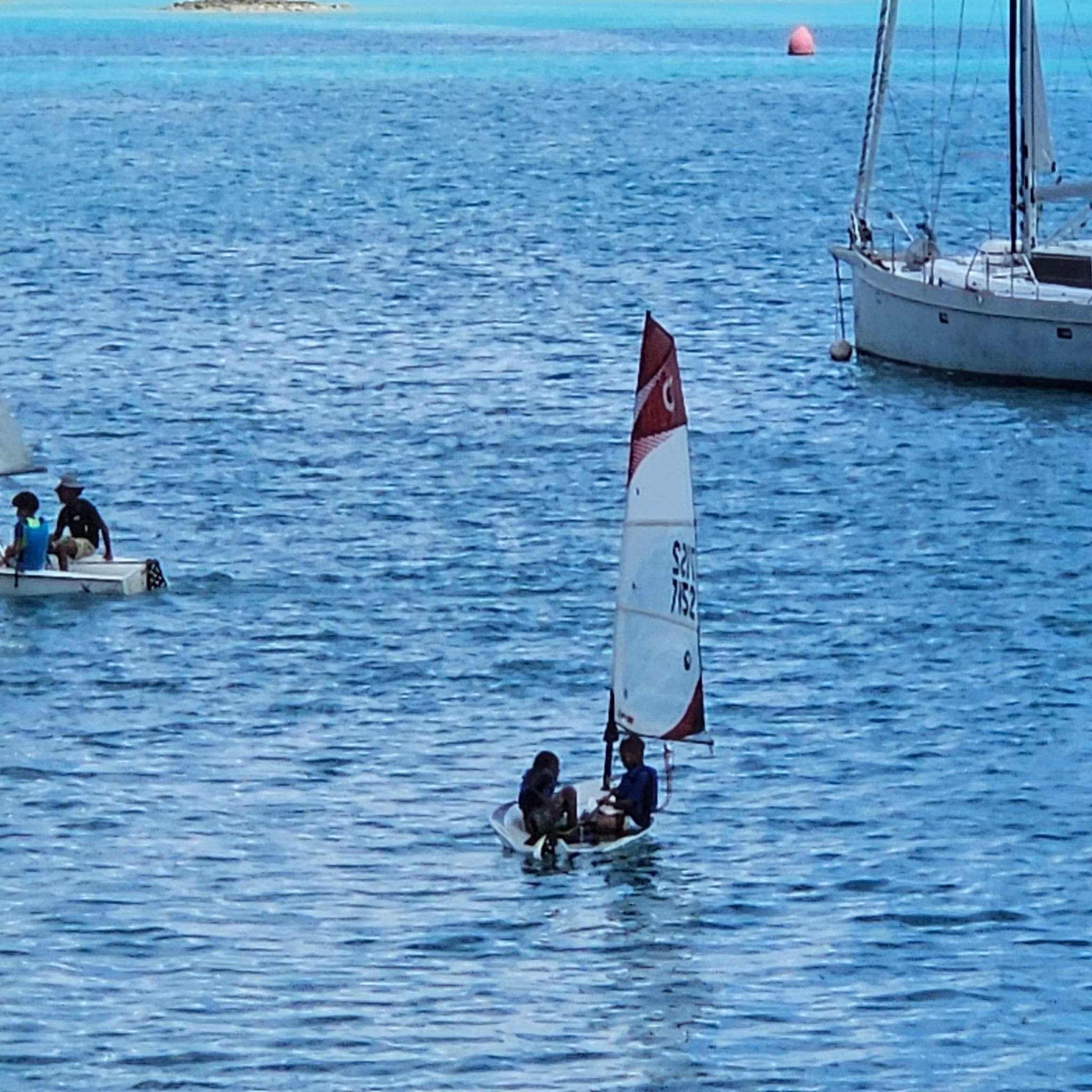 Young sailors in an Optimist on turquoise water